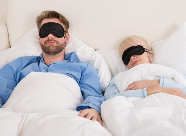 couple sleeping peacefully in bed with eye masks on