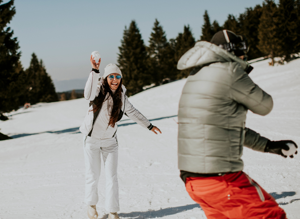 couple having a snowball fight on snowy mountain to burn holiday calories