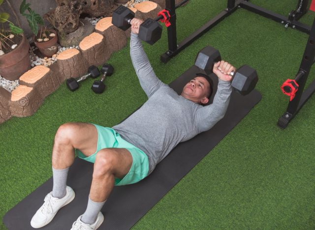 man demonstrating dumbbell chest press on floor to increase your muscle power