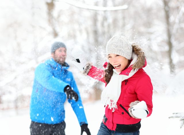 fit couple engaging in snowball fight outdoors