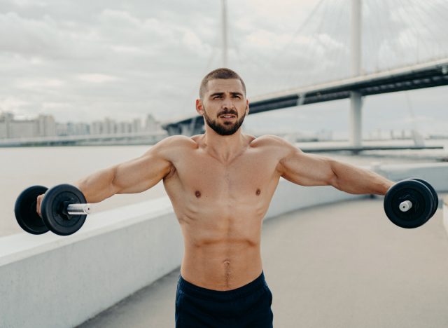 muscular man performing dumbbell exercises to build up boulder shoulders