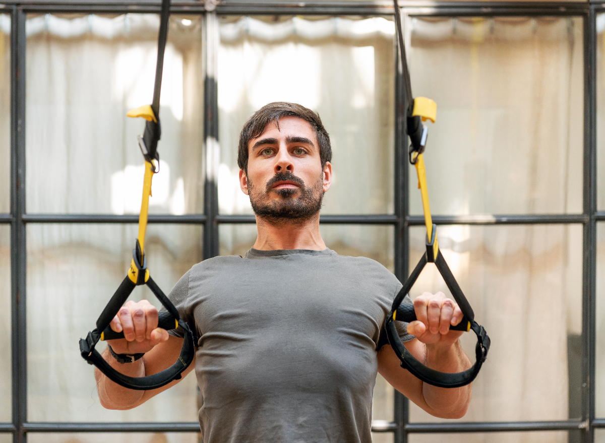 fitness man working out with TRX straps, concept of how to gain muscle without gaining fat