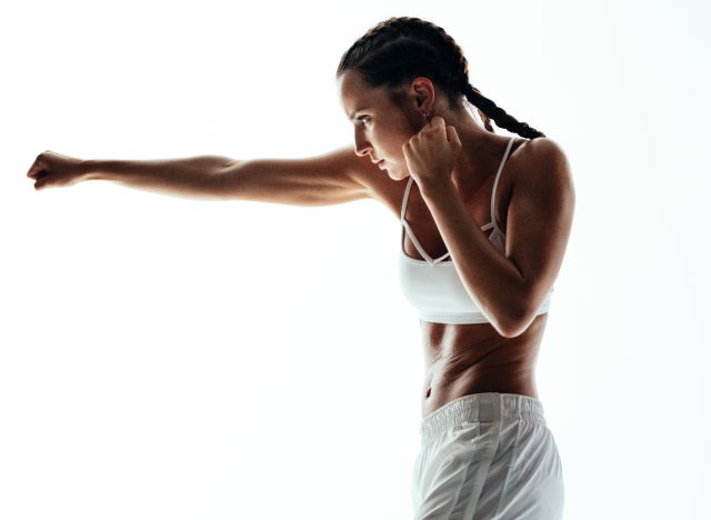 fitness woman shadowboxing in front of white background