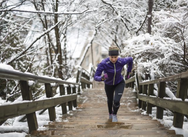 fitness woman running up steps, snowy backdrop