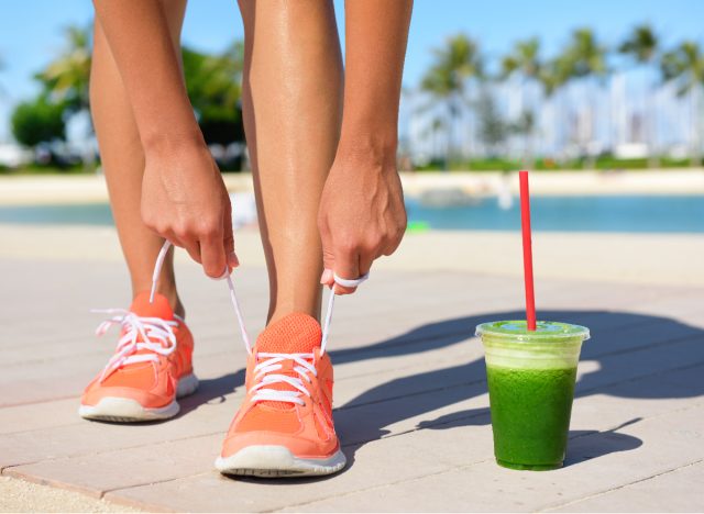 fitness woman tying sneakers next to green smoothie, weight loss tips concept