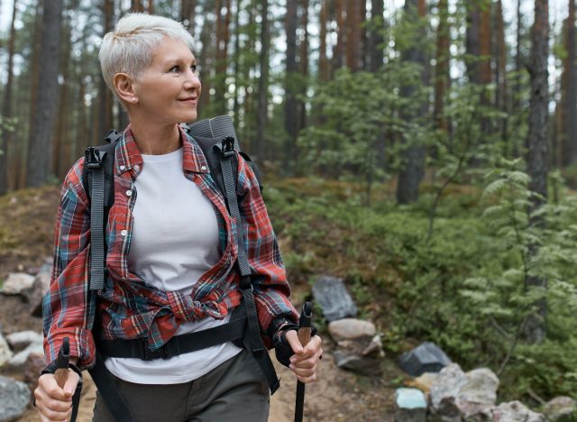 A mature woman in nature walking, showing the daily habits of a flat belly
