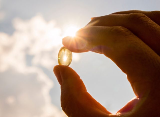 holding vitamin d capsule against the sun