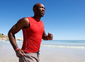 man running on beach, demonstrating how to get rid of moobs with cardio