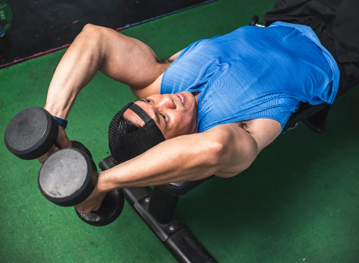 man performing dumbbell bench exercises to eliminate man boobs