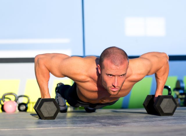 man performing dumbbell pushups to eliminate man boobs