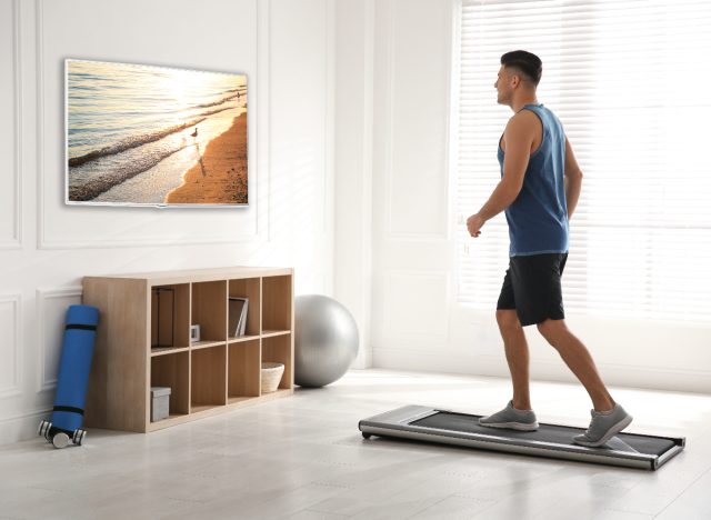 man doing easy cardio exercises on treadmill pad at home while watching TV