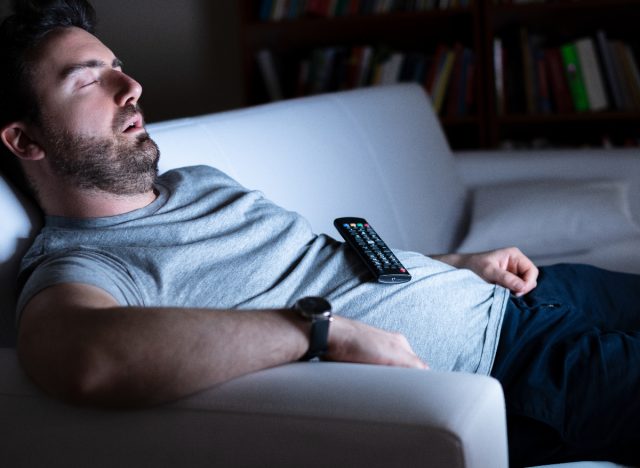 man experiencing junk sleep in front of the TV at home