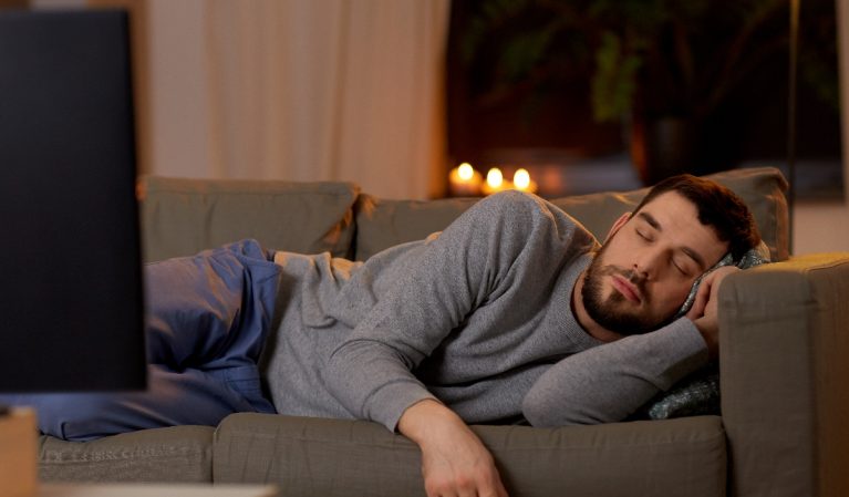 man napping getting junk sleep on couch in front of TV