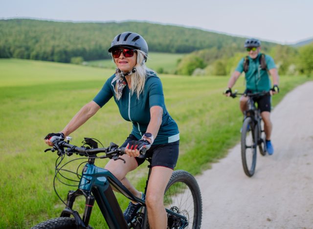 mature couple bike riding outdoors on trail to prevent muscle loss