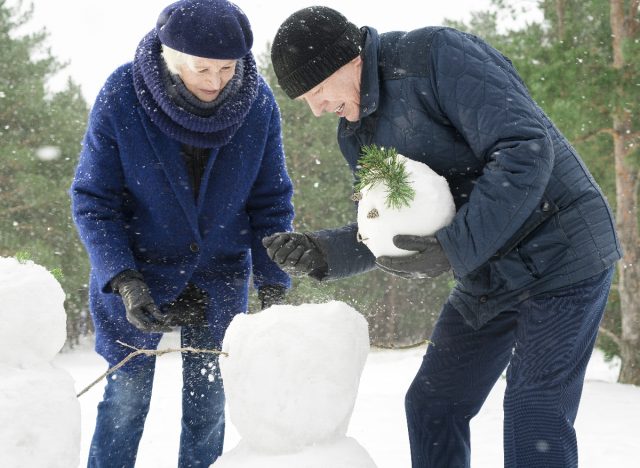 mature couple building snowman