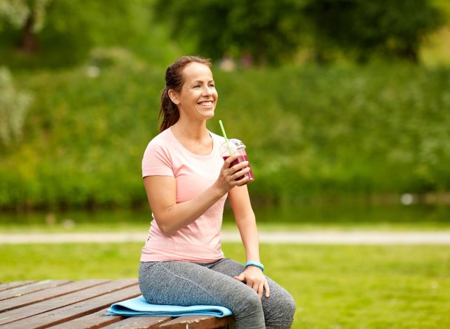 active middle-aged woman enjoying healthy smoothie outdoors