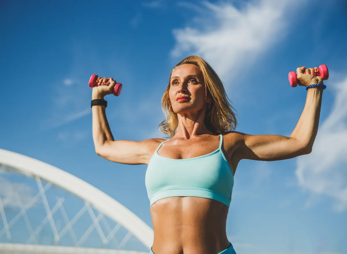 middle-aged woman holding up dumbbells, maintain muscle mass after 50 concept