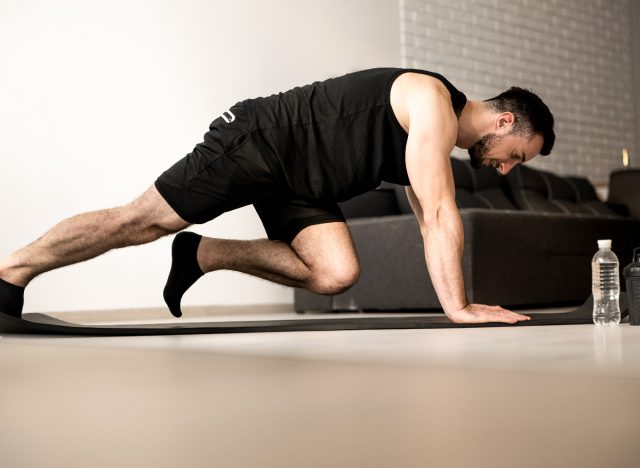 man performing mountain climbers from his living room, couch exercises to get rid of holiday weight gain