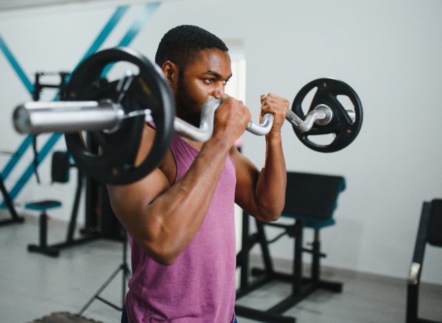 muskulös man på gym lyft skivstång