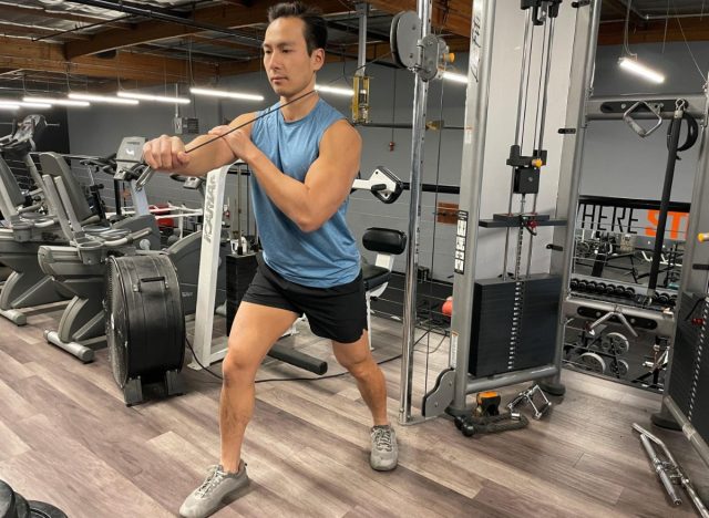 trainer demonstrating one-arm cable triceps extension