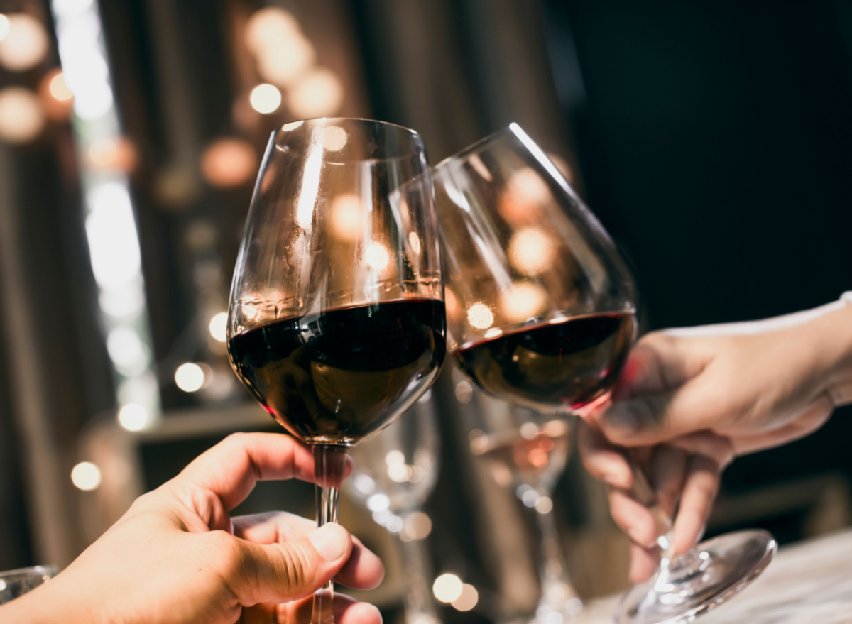 people holding red wine glasses