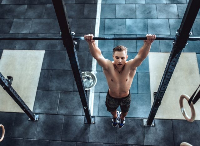 fitness man performing the dead hang exercise with pull-up bar