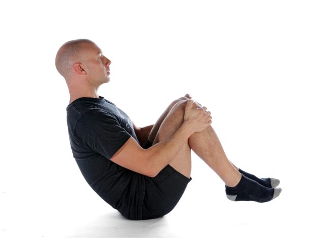 man demonstrating rolling like a ball exercise