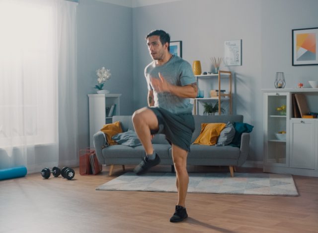 A man jogging in place at home, doing easy cardio while watching TV