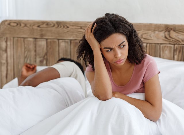 annoyed woman sharing a bed with restless partner