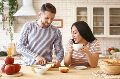 Couple slicing apples and drinking tea in the kitchen.