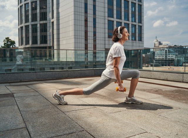 mujer madura haciendo ejercicios de sentadilla dividida con mancuernas para recuperar el equilibrio después de 60