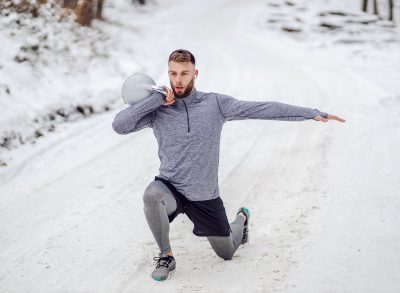 man performing split squat lunges exercises for chicken wings in the snow