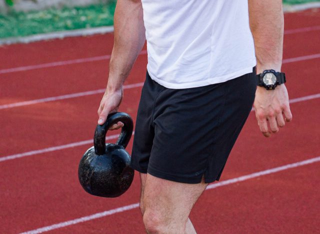 man doing close-up suitcase carry standing ab exercises on track