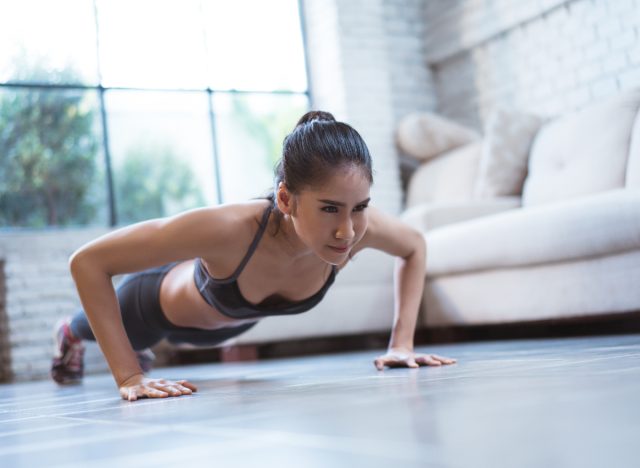fitness woman doing pushups at home in her living room