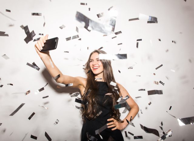 woman taking New Year's selfie with confetti