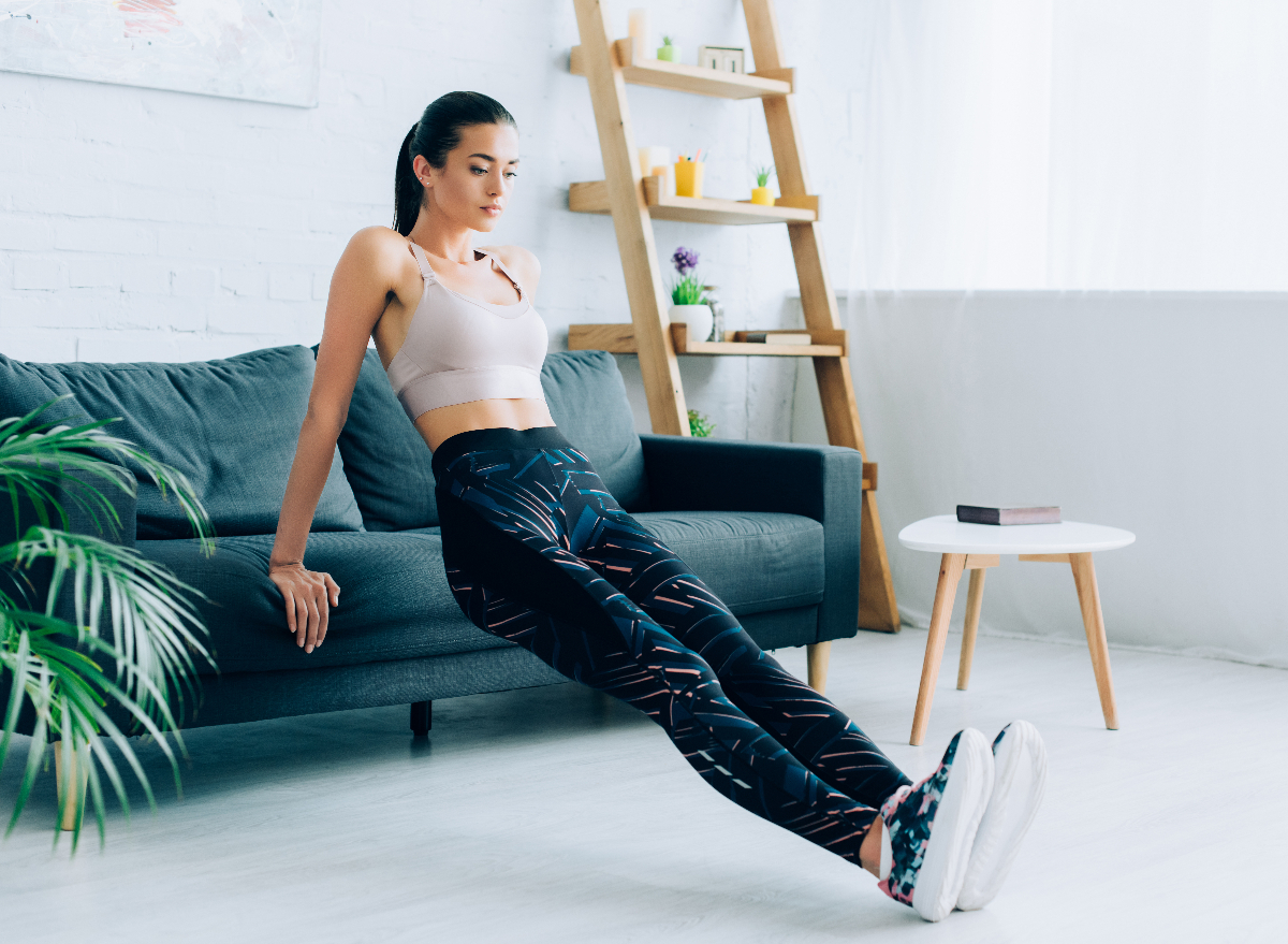 woman demonstrating couch dips exercise in bright living room to get rid of holiday weight gain