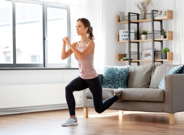 kvinna gör soffa Bulgarian split squats i hennes vardagsrum