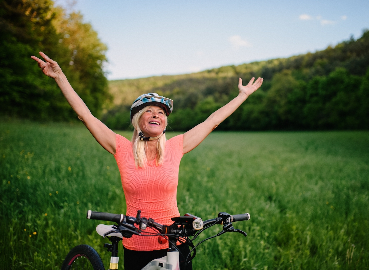 happy mature woman cycling, performing exercises to improve coordination after 60