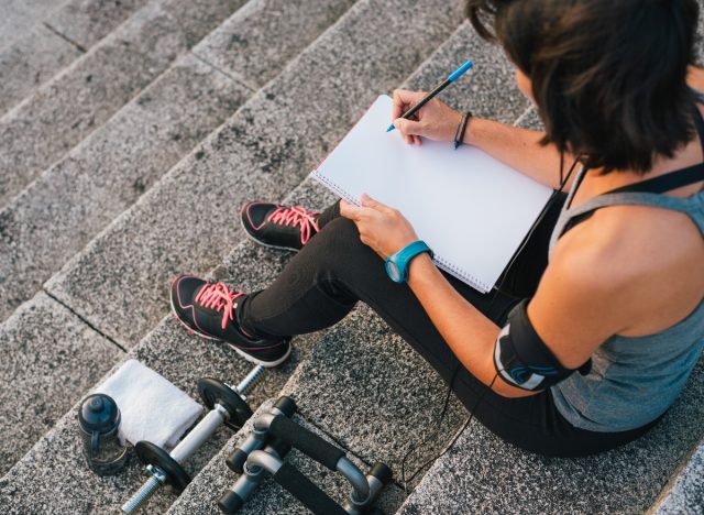 fitness kvinna skriva ner sina träningsmål