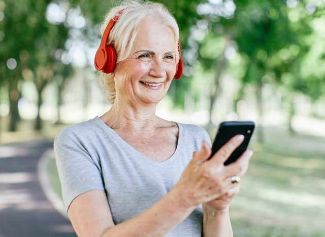 Woman listening to a podcast during a walk outdoors on a bright sunny day