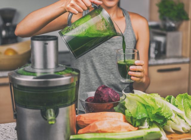 woman pouring green juice into glass