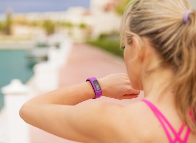 Close-up woman checking fitness tracker on watch while walking for weight loss