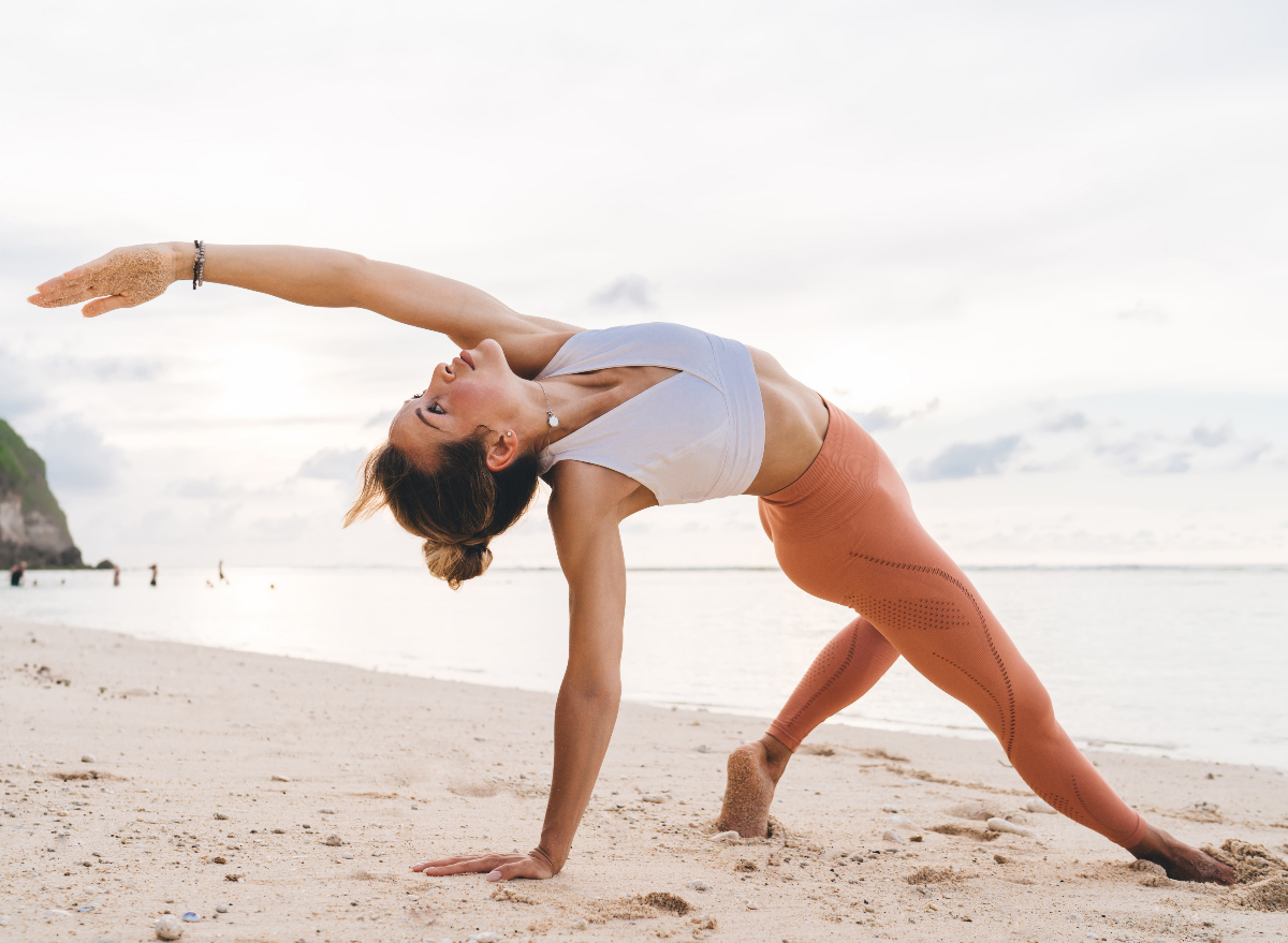 woman doing yoga on the beach, demonstrating how to age-proof your back