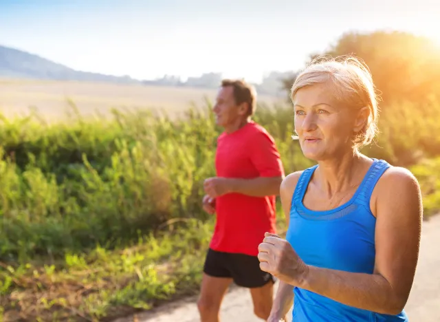 active senior couple walking outdoors in the summertime on trail, demonstrating how to improve your endurance