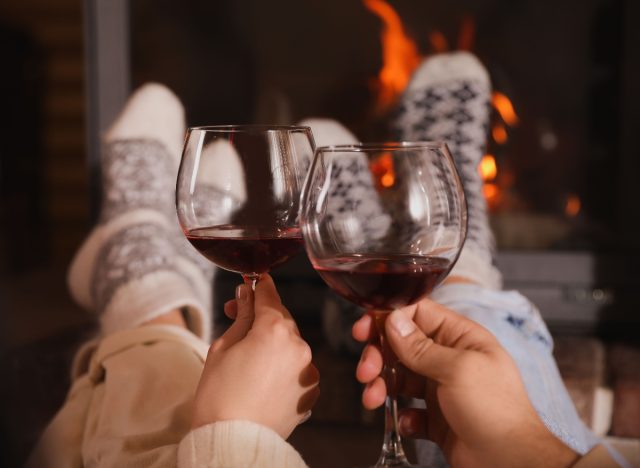 couple toasting wine glasses by fireplace