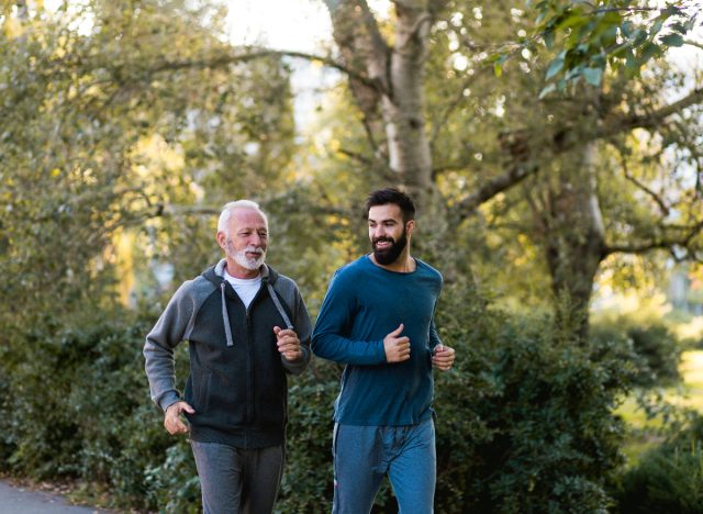 father and son jogging outdoors on trail with foliage