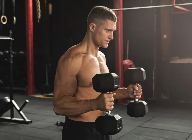 fitness man at gym doing bicep hammer curls with dumbbells to get bigger arms