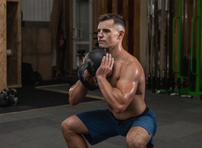 fitness man at gym demonstrates kettlebell workout to improve muscular endurance