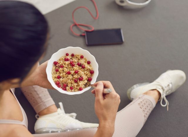 fitness woman close-up eating oatmeal on a yoga mat before training, shows how to lose a lot of weight