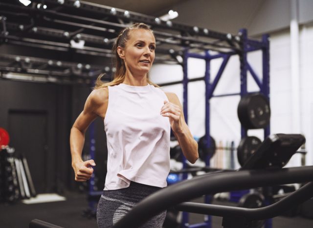 fitness mature woman running on treadmill at gym